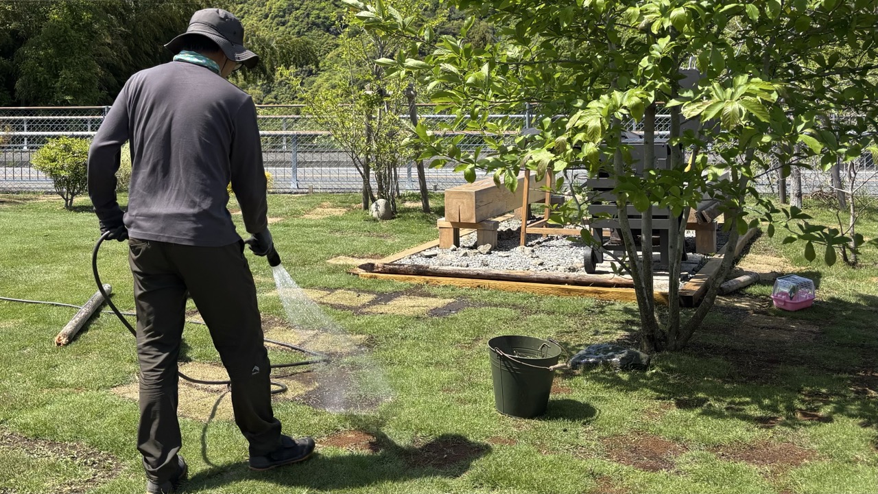 相模原のセカンドハウスモッケヤの庭で芝に水やりをする男性
